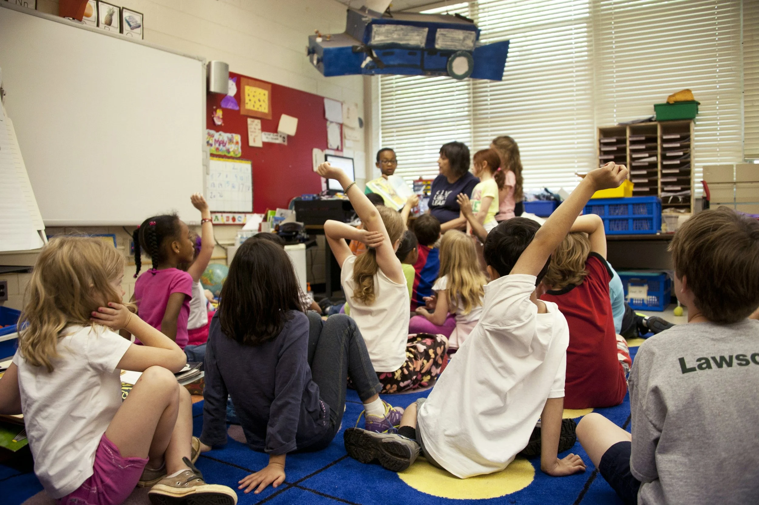 Children raising hands in an engaging classroom setting